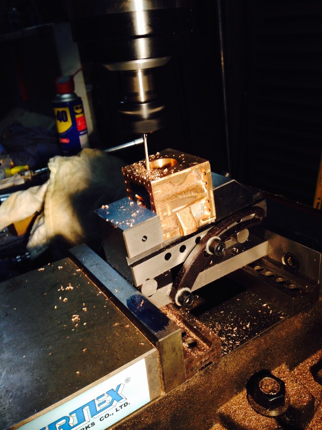 This is the drilling setup. I used a sine vice, sitting on gauge blocks, to produce an exactly 5 degree angle, to avoid the cylinder bore and the bolt holes. The sine vice was held in the milling vice.